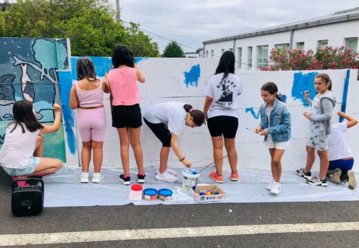 Nenas e nenos do ‘Verán Lúdico’ de Touro pintan o mapamundi nun dos muros que circunda o CPI Fonte Díaz, onde a próxima semana comezará o novo curso